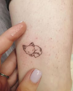 a woman's arm with a small tattoo of a sleeping fox on her left side