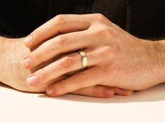 a close up of a person's hand with a gold ring on it,