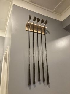 four golf clubs are hanging on the wall