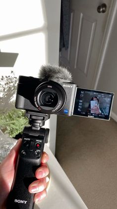 a person holding a camera with a microphone attached to it