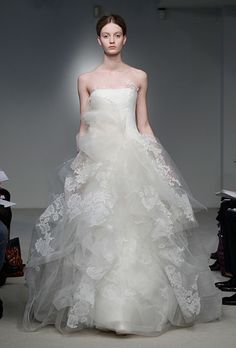 a woman in a white wedding dress walking down the runway