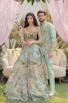 a man and woman standing next to each other in front of a floral decorated backdrop