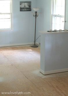 an empty living room with hard wood flooring and white walls, two windows on the far wall