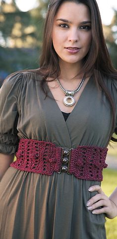 a beautiful young woman wearing a brown dress and holding her hand on her hip while standing in the grass