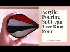 a person holding a red, white and black object in their hand with the words acrylic pouring split - cup tree ring pour