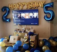 balloons and streamers are scattered around the table for a birthday party with blue, gold and white decorations