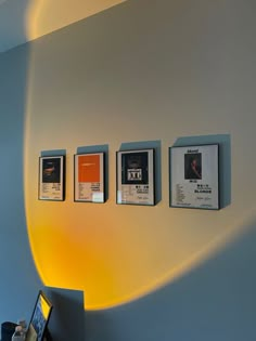 a wall with three framed pictures on it and a laptop computer sitting next to it