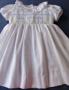 White dress hand smocked with delicate light blue crosses. Ties on the back Easter dress or christening dress is a beautiful dress delicately smocked with crosses. This dress can also be used not just for that special occasion or for any other special event, dedication or for older girls their First Holy Communion and portraits. Made to order. For customs made orders allow 2-3 weeks for delivery. Elegant Smocked Dress With Smocked Cuffs For Baptism, Elegant Smocked Ruffle Dress For Baptism, Elegant Baptism Dress With Smocked Back, Elegant Dress With Smocked Back For Baptism, Elegant Smocked Dresses For Baptism, Elegant Baptism Dress With Smocked Bodice, Elegant Smock Dresses For Baptism, Elegant White Smocked Dress For Baptism, Fitted Dress With Smocked Bodice For Baptism