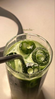 a glass filled with green liquid on top of a table