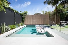 an outdoor swimming pool surrounded by trees and plants with white balls on the ground in front of it