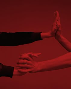 three people are holding their hands together in the air with red lighting behind them and one person is reaching out for something