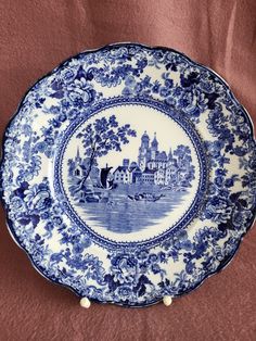 a blue and white plate sitting on top of a brown cloth covered table next to a wall