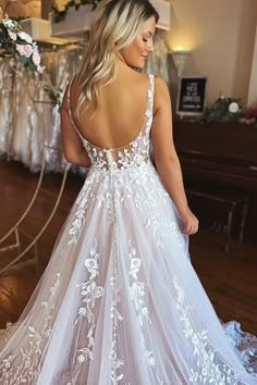 a woman in a white wedding dress standing on a wooden floor with her back to the camera