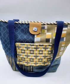 "This bright yellow/blue with a variety of geometric designs was made from upholstery samples. Each block is unique. The back of the purse has more green/blue combinations. The top is piped in bl/cream stripe with a navy blue 26\" set of straps. The purse is secured by vinyl tab and velcro. The tiny blue button gives is flair. The outside pocket also has velcro & 3 inside pockets give extra organization. The purse measures: h-15 1/2\"; w-11\"; bottom width'6 1/2\". Great as a purse or tote for o Yellow Rectangular Shoulder Bag With Pockets, Rectangular Yellow Shoulder Bag With Pockets, Yellow Square Shoulder Bag For Daily Use, Yellow Square Shoulder Bag With Handles, Yellow Square Bag, Yellow Square Bags, Retro Blue Bags With Pockets, Everyday Square Yellow Bag, Blue Reversible Rectangular Bag