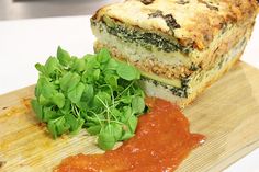 a close up of food on a cutting board with sauce and greens next to it