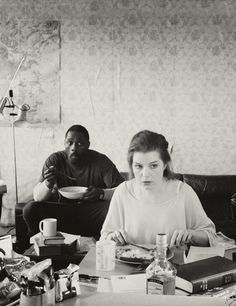 black and white photograph of two people sitting at a table with food in front of them