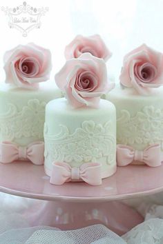 three wedding cakes decorated with pink roses on a cake plate