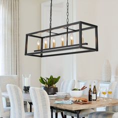 a chandelier hanging over a dining room table with chairs and plates on it