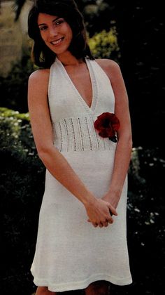 a woman in a white dress is holding a red rose and posing for a photo