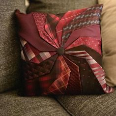 a decorative pillow is sitting on a couch with some pillows in the shape of an origami flower