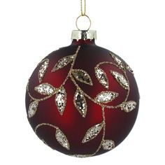 a red ornament with silver leaves on it's side, hanging from a gold chain