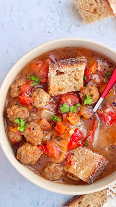 a bowl filled with meat and vegetable soup next to slices of bread on the side