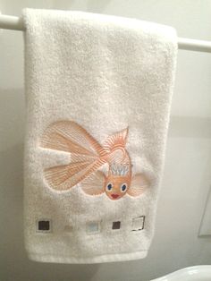 an orange fish on a white towel hanging from a wall