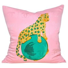 a pink pillow with a green and gold leopard on it's back, sitting on top of a blue ball