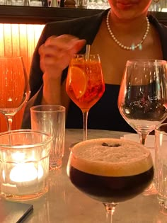 a woman sitting at a table with several wine glasses and drinks in front of her