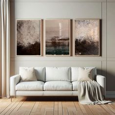 a living room with three paintings on the wall and a couch in front of it