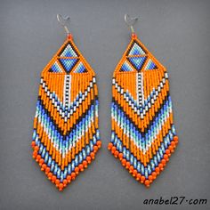 an orange, blue and white beaded earrings on a gray surface with silver hooks