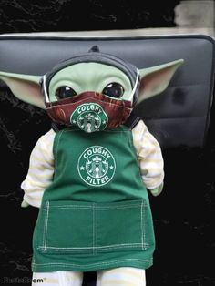 the baby yoda doll is wearing a starbucks mask and green overalls with white stripes