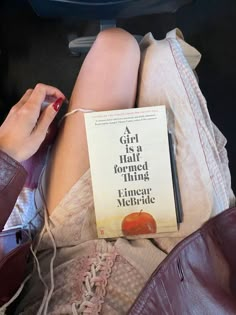 a woman is laying down with her legs crossed and holding a book in her lap