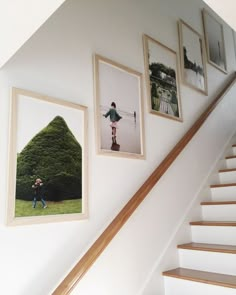 three framed photographs hang on the wall next to a stair case