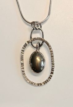 Pyrite stone (10 x 14 mm) set in fine silver bezel hanging from 32 x 24 mm hammered Sterling Silver ring Silver Oval Pendant Jewelry With Large Stone, Modern Nickel-free Oval Jewelry, Silver Jewelry With Polished Oval Cabochon, Modern Oval Cabochon Jewelry With Large Stone, Modern Silver Jewelry With Large Stone, Modern Silver Oval Pendant Jewelry, Silver Hammered Oval Pendant Jewelry, Oval Oxidized Metal Jewelry, Hammered Sterling Silver Oval Jewelry