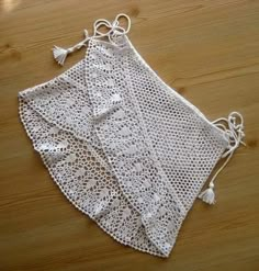 a white crocheted doily with tassels on a wooden table top