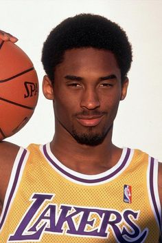 a man holding a basketball in his right hand and wearing a lakers jersey on the left