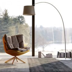 a living room with a chair, lamp and bookshelf in front of a large window