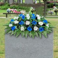 blue and white flowers are placed on the base of a grave in a park setting