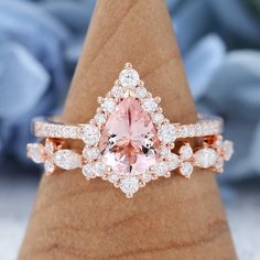 a pink diamond ring sitting on top of a wooden stand