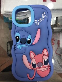 a phone case with an image of stitch and baby stitch on it, in front of some other items