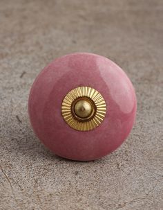 a close up of a pink object with a gold knob on it's end