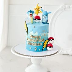 a pokemon themed birthday cake on a white pedestal