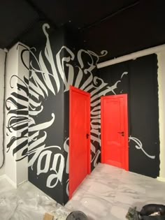 two red doors are in the middle of a black and white room with graffiti on it