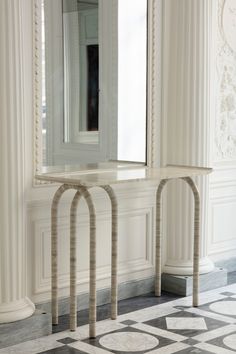 a mirror sitting on top of a white table next to a black and white checkered floor