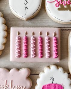 decorated cookies with pink icing on top of a wooden table