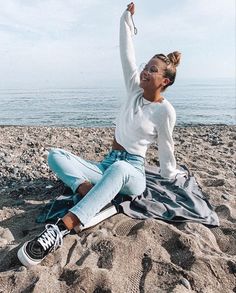 a woman sitting on top of a sandy beach