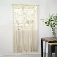 a vase filled with flowers on top of a wooden table next to a window covered in sheer curtains