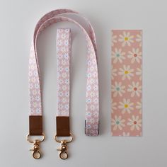 a pink and white flowered leash with two caramel colored metal hooks on it