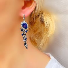 Make a lasting impression with these beautiful, elaborate sapphire drop earrings framing your face. Crafted in sterling silver with a platinum anti tarnish finish, each cascading drop dazzles with a series of sparkling round and oval cut genuine blue sapphires arranged in a mesmerizing leaf-like pattern down the length of the design. Buffed to a brilliant luster and sure to receive second looks, these extravagant latch back earrings secure comfortably. Earrings measure 14 mm width at widest point and 60 mm drop length. Large sapphire stone at the top of earring measures 10 mm  by 14 mm. Measurements of top stone with white topaz surround is 14 mm by 17 mm September birthstone. 45th wedding anniversary gemstone  Please provide us with a telephone number if you choose International FedEx Exp Blue Dangle Chandelier Earrings For Anniversary, Elegant Long Drop Blue Jewelry, Blue Chandelier Drop Earrings For Anniversary, Elegant Blue Chandelier Earrings For Evening, Sapphire Dangle Earrings For Evening, Silver Sapphire Dangle Jewelry, Elegant Blue Long Drop Chandelier Earrings, Unique Blue Long Drop Earrings, Elegant Sapphire Dangle Earrings